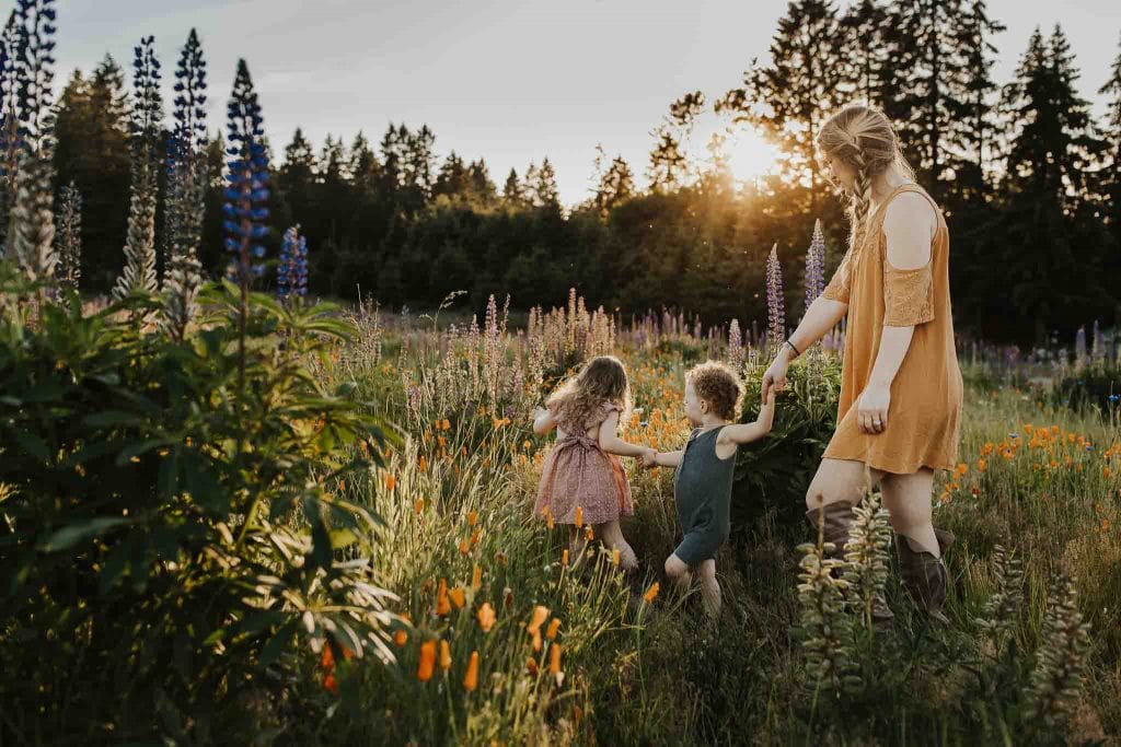 two young kids leading mom through field of flowers - outdoor family photos in portland