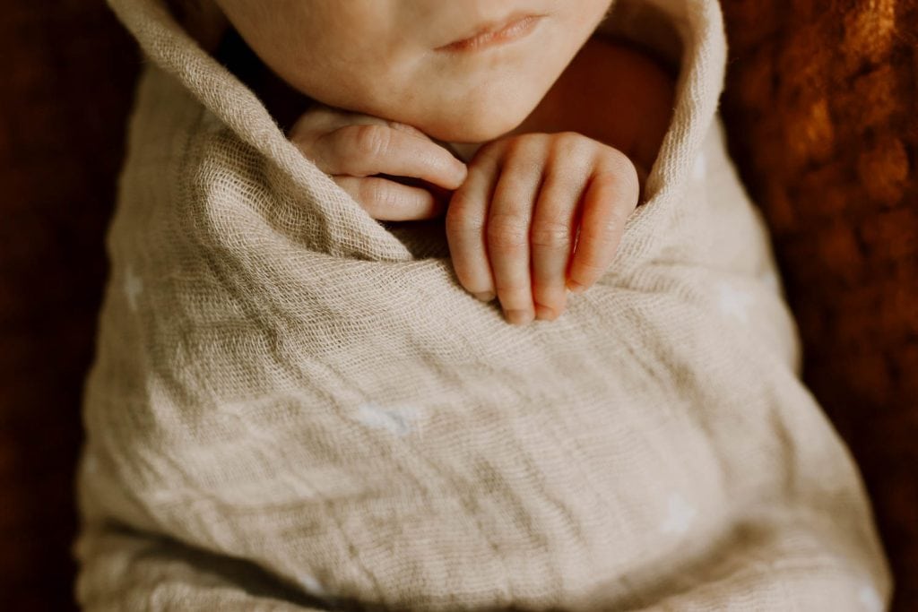 closeup of newborn infant's hands under her chin - newborn photographer pdx