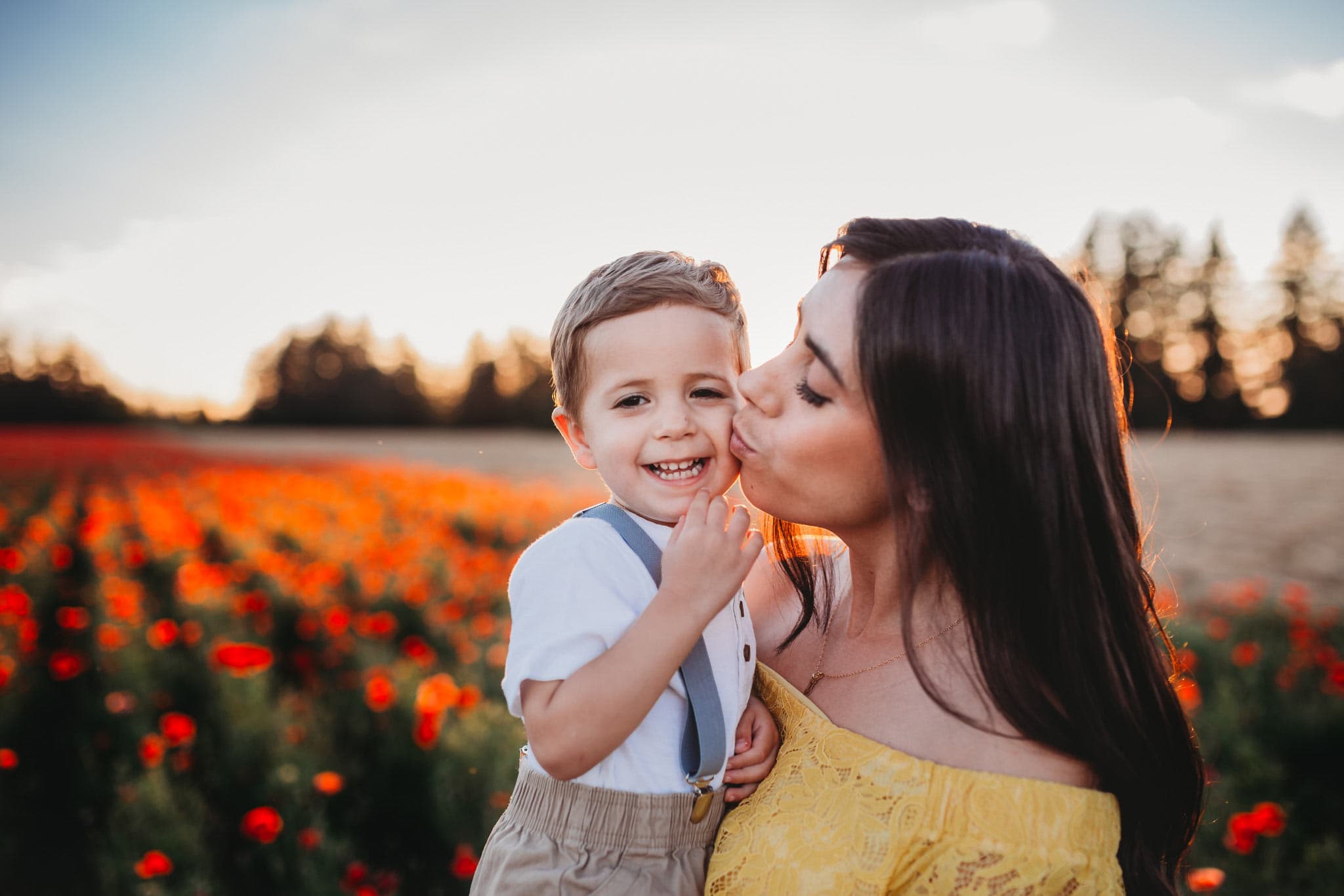 Mom kissing son on the cheek with field behind