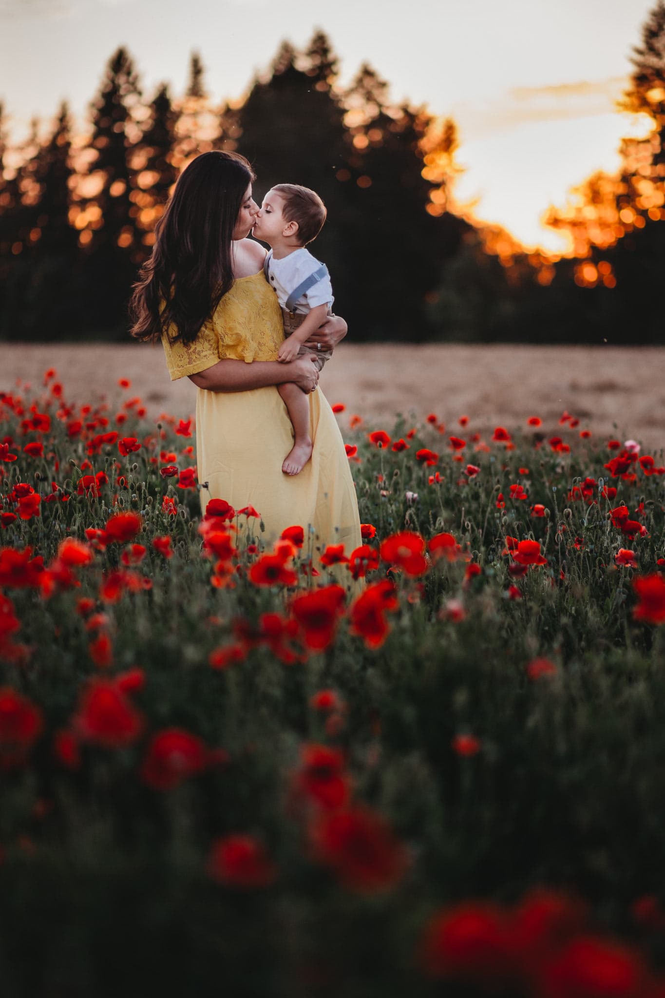 Mom and toddler kissing with Poppy flowers surrounding them