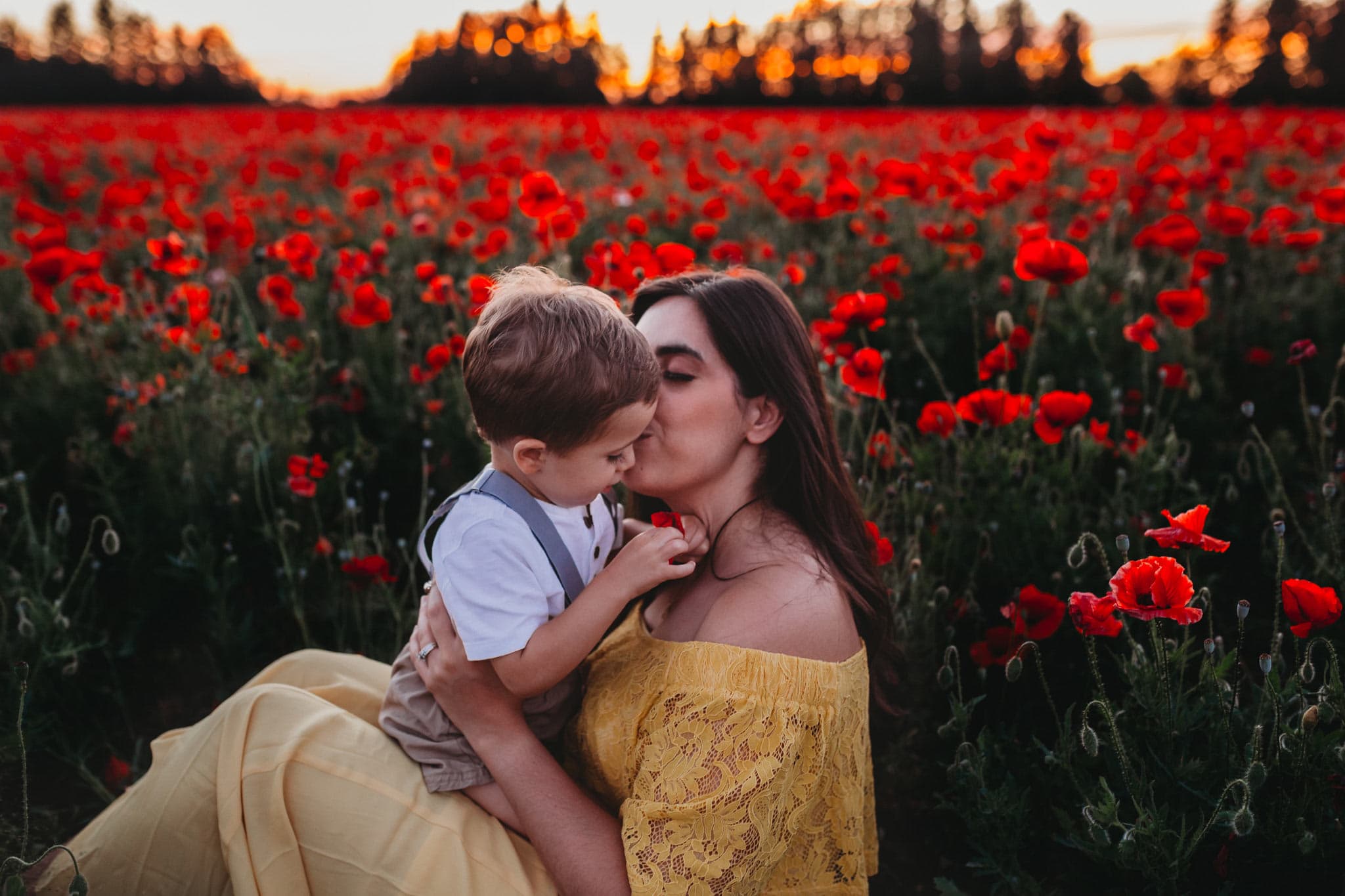 Mom kissing son sitting in front of red poppies