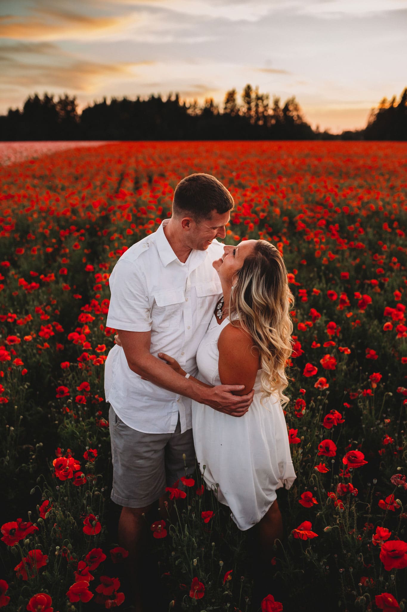 Couple smiling at each other with poppies surrounding them