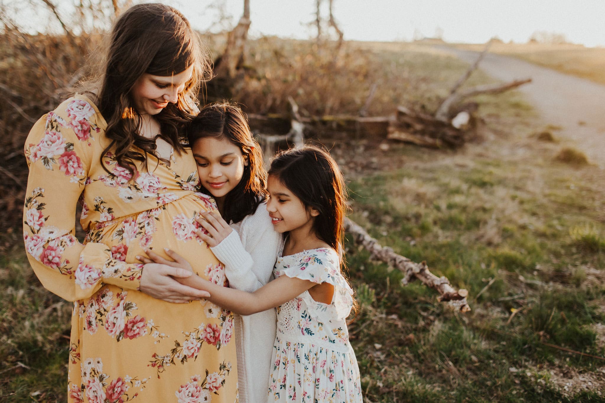 sisters hugging their pregnant mama during their Lifestyle Maternity Family Photography Session