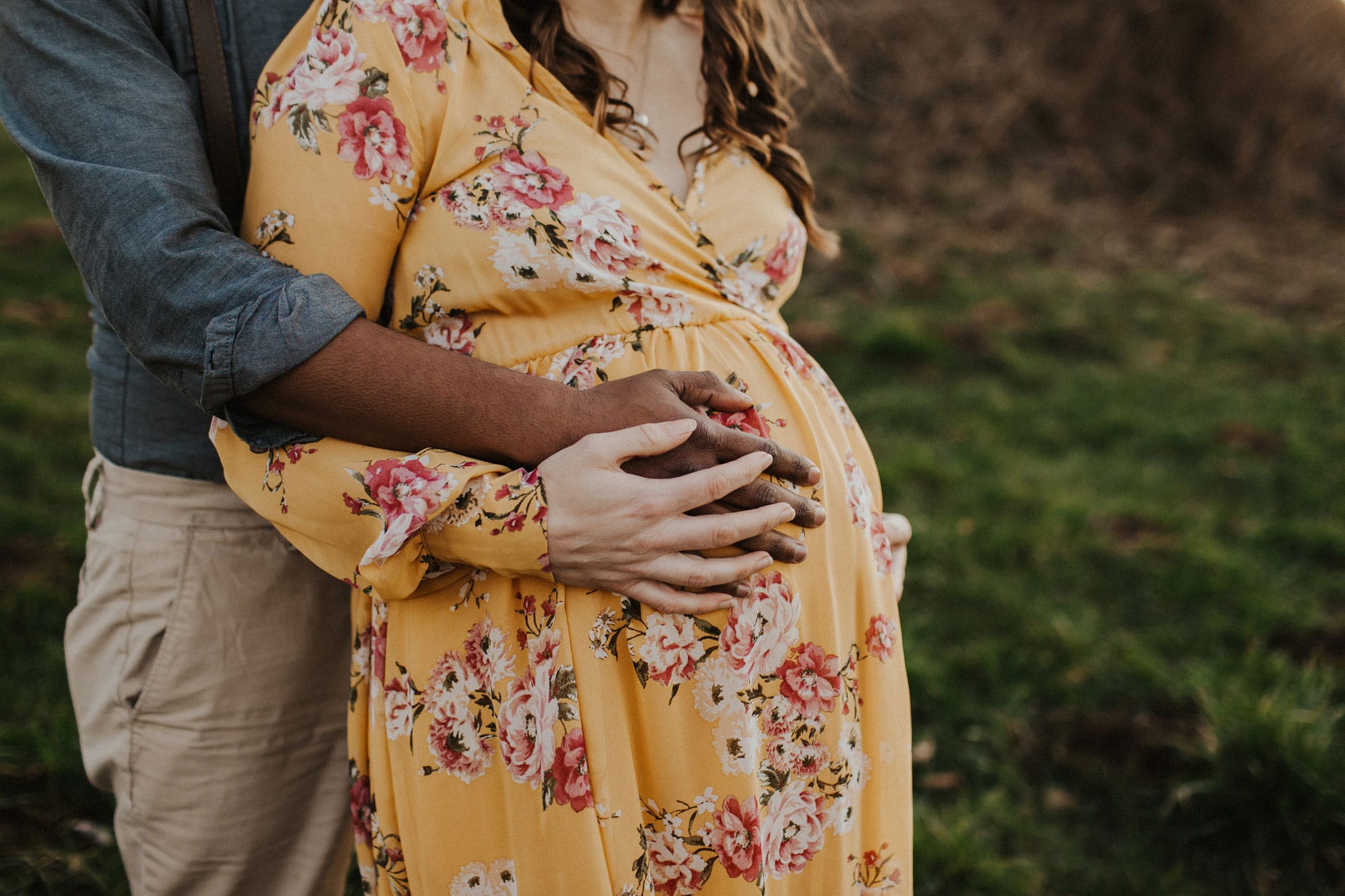 professional photography closeup of maternity belly with husband hugging mama