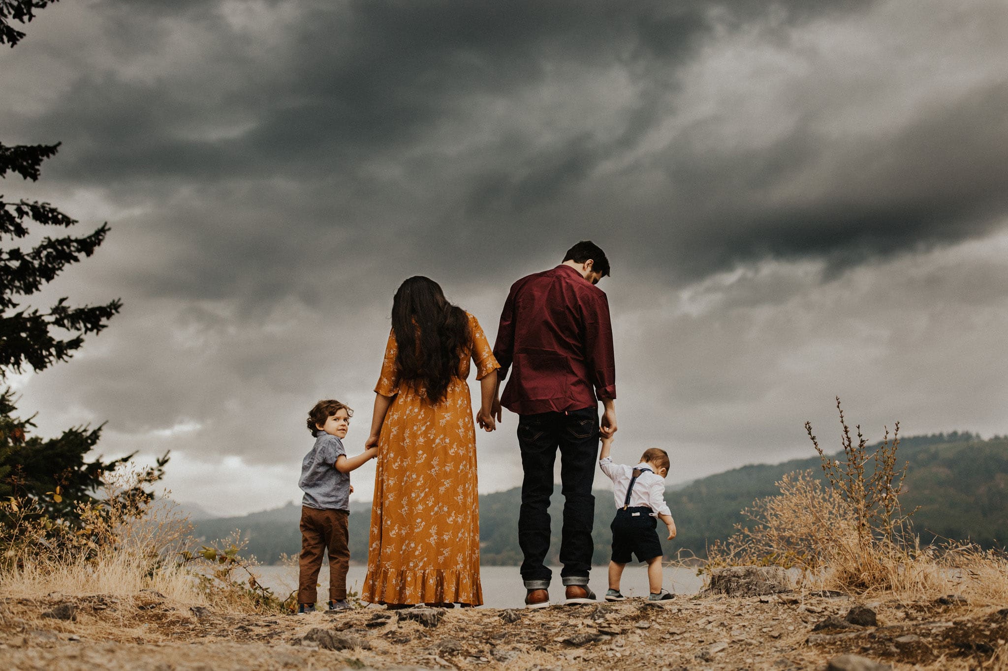 family standing holding hands with cloudy skies above