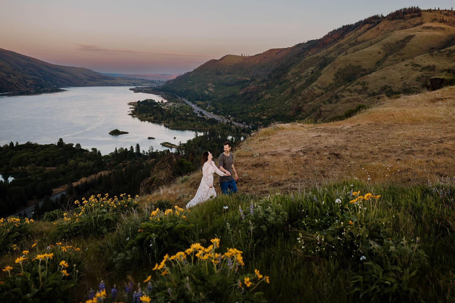 Married couple holding hands while walking above the columbia river gorge