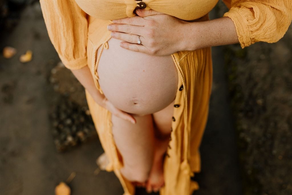 closeup of pregnant bare belly in a mustard yellow dress form Jens Pirate Booty