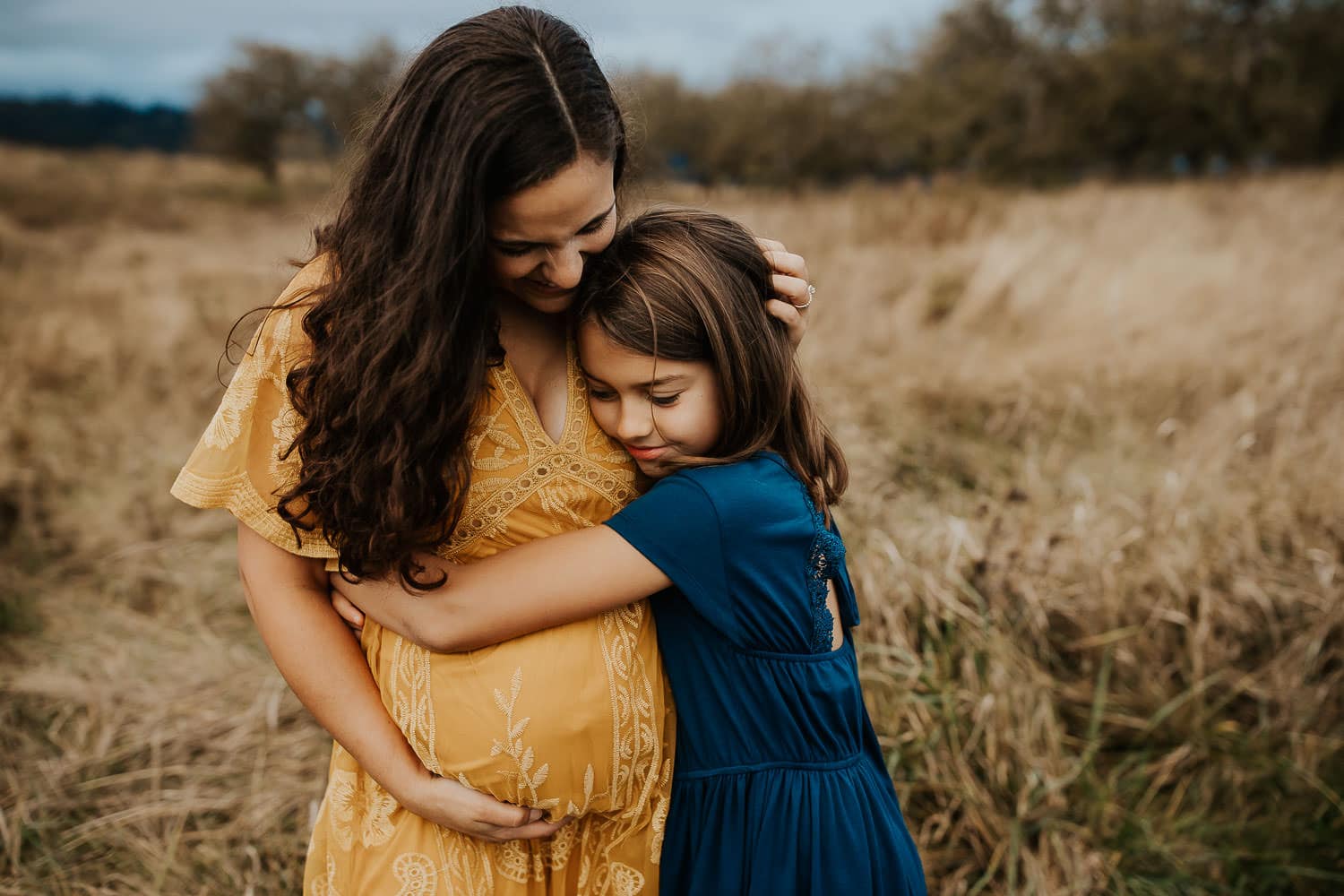 little girl hugging her pregnant mom - what to wear for maternity photos