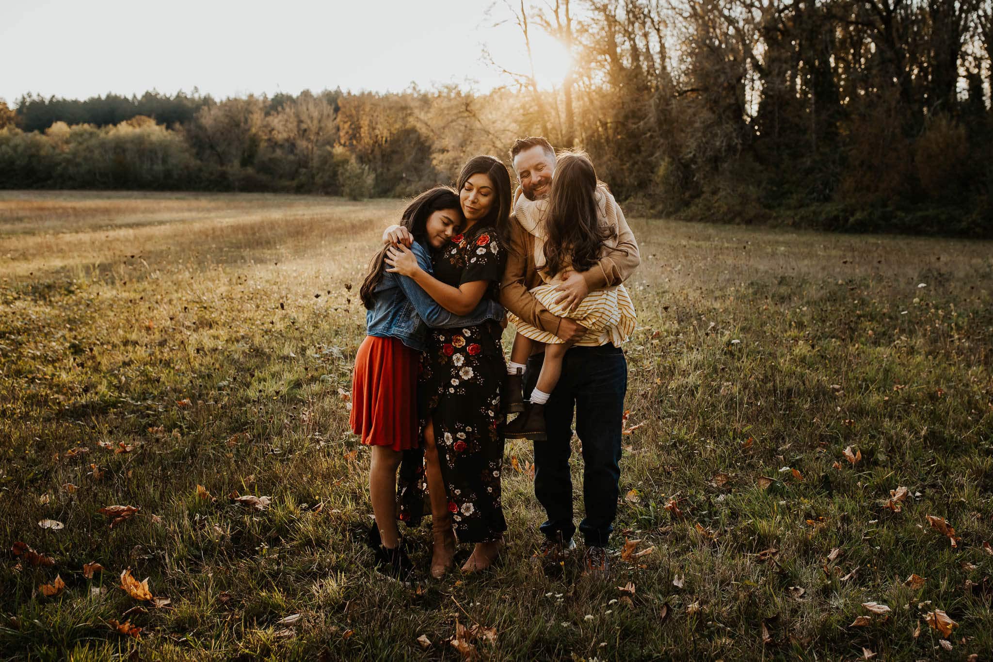 Family hugging and being sweet and candid in the middle of a field in Portland oregon