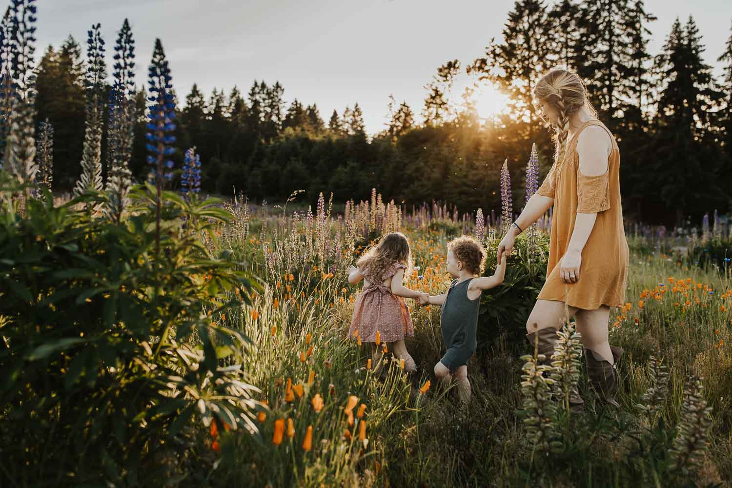 Mom with her two kids holding hands and walking through a field of wildflowers in Oregon City