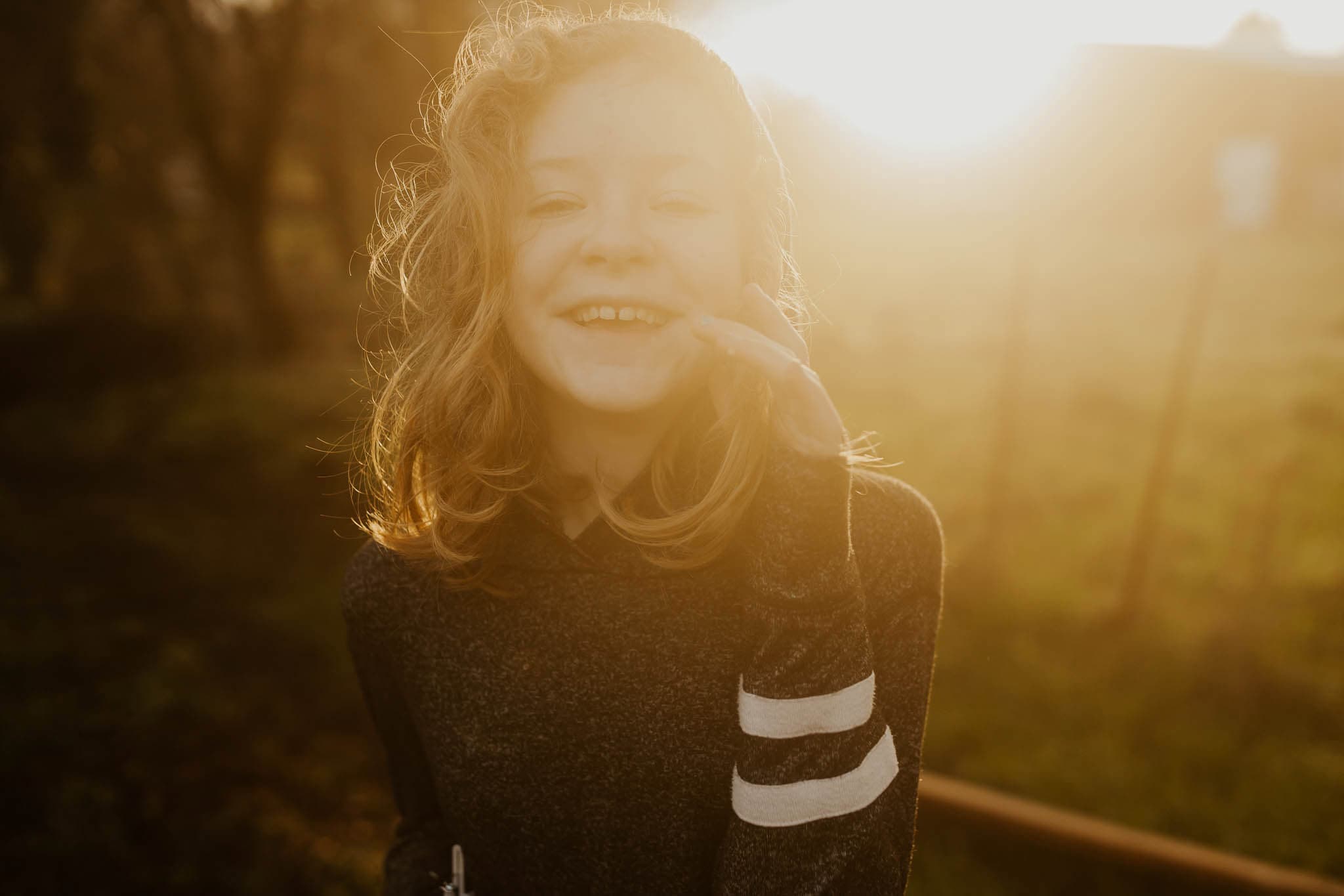 Creative Photography Ideas- closeup of 10 year old girl laughing with golden sun behind her - Cinebloom filter