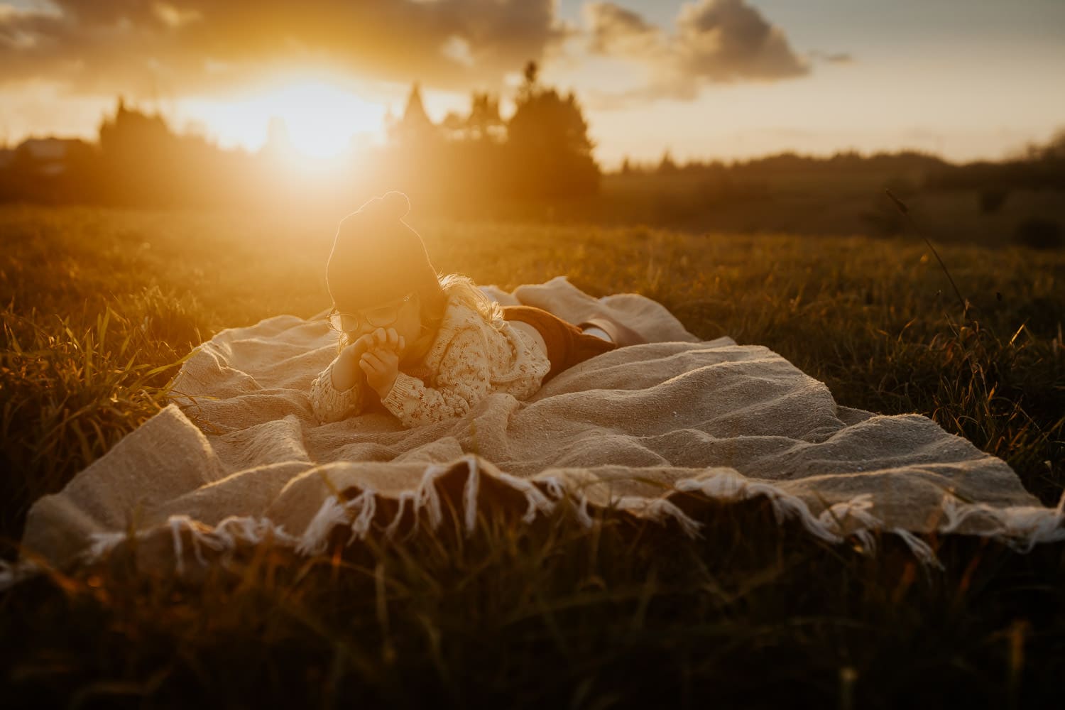 three year old girl laying on blanket with hazy sun behind her - creative photography ideas with the cinebloom camera lens filter