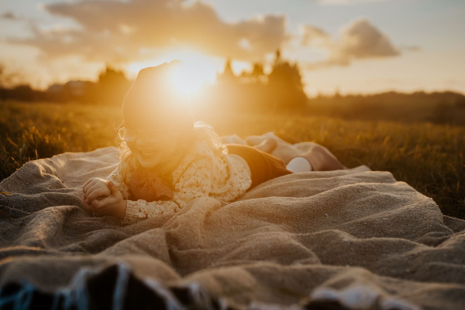 Creative Photography Ideas- photo of three year old girl on a blanket with hazy golden sun behind her