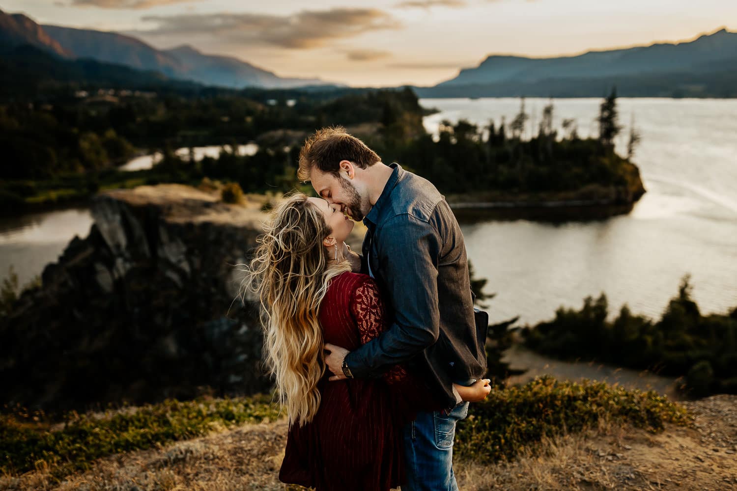beautiful couple kissing with the eind blowing and the columbia river gorge in the background - best couples photography locations