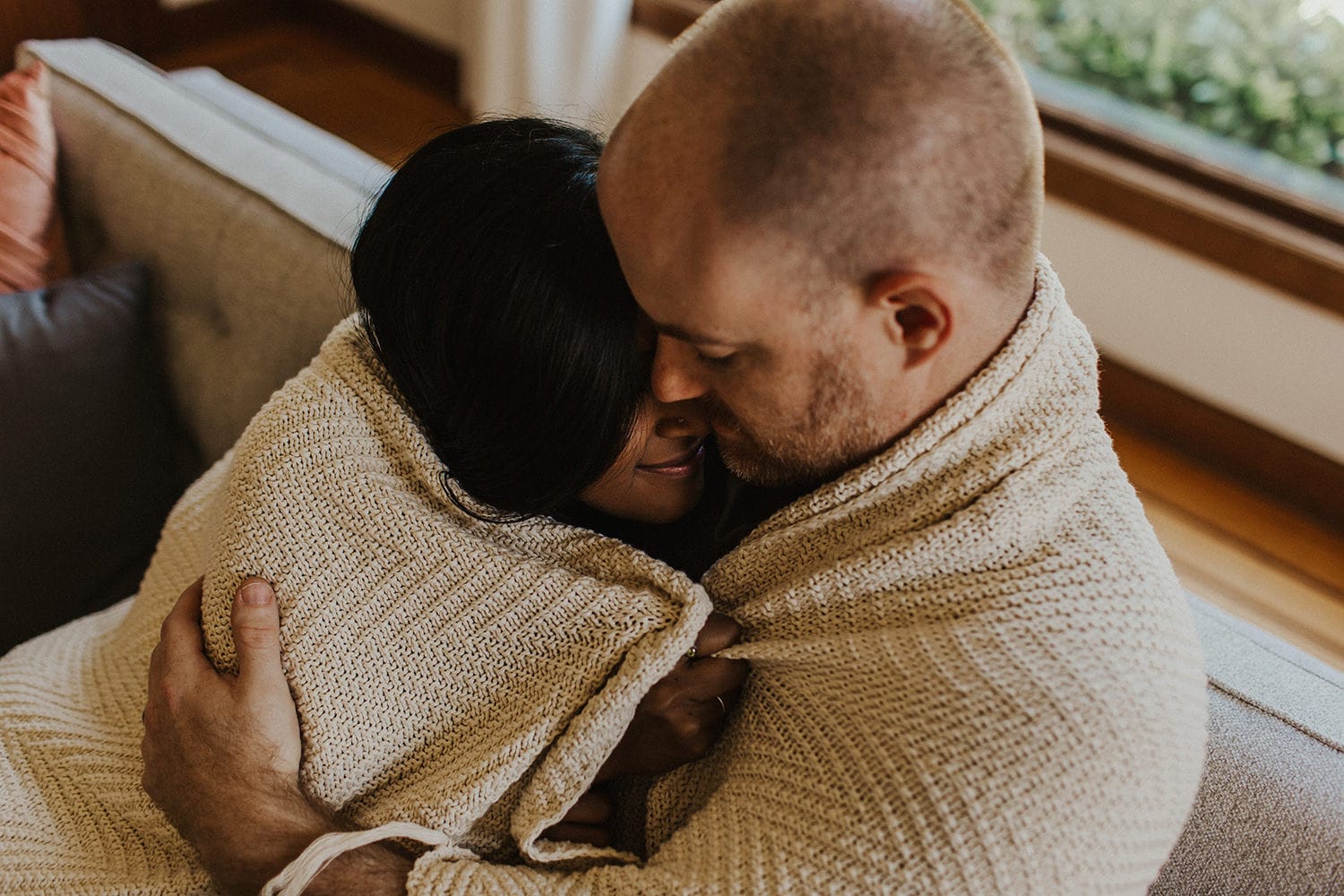 portland couple snuggling in a blanket on the couch - anniversary date night ideas