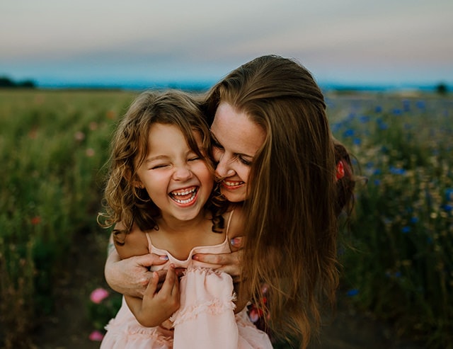 Mom and 5 year old daughter laughing hard with their faces close together during their family photos in Portland Oregon