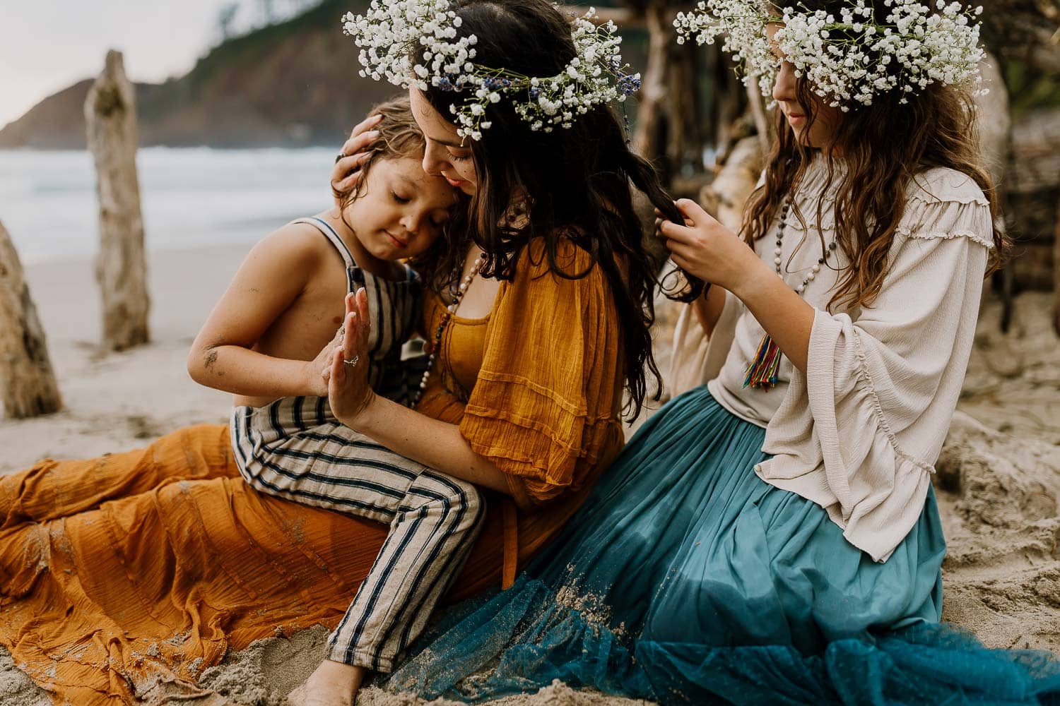 Mom in a caramel free people dress and daughter playing with her hair wearing Joyfolie outfit, with little boy on moms lap