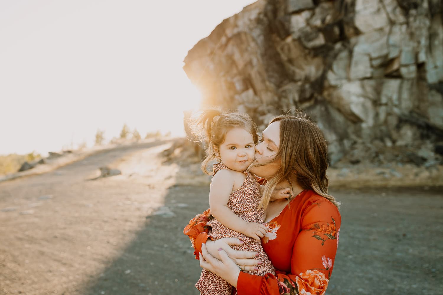 mom kissing toddler daughter with rocks behind them in the gorge