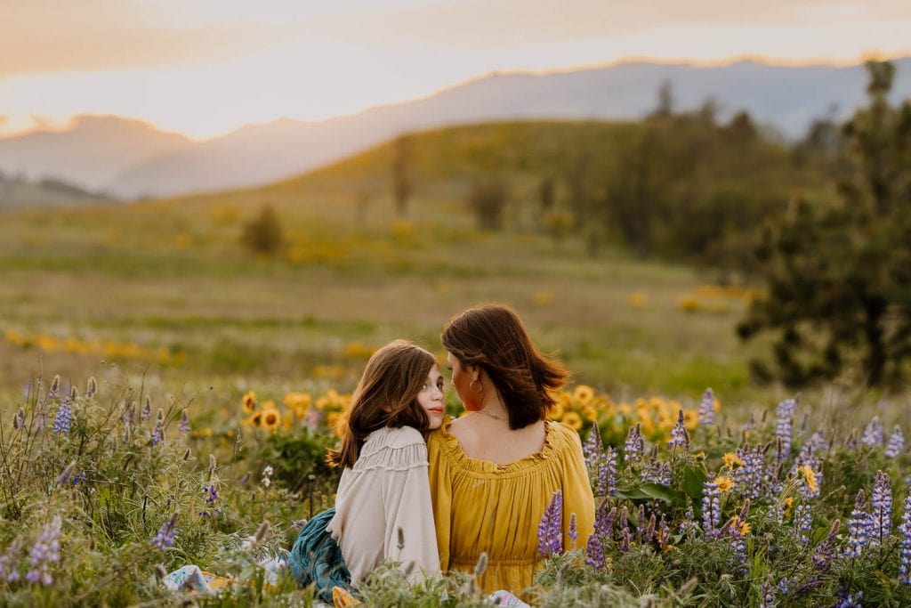 Mom and daughter sitting in field of flowers