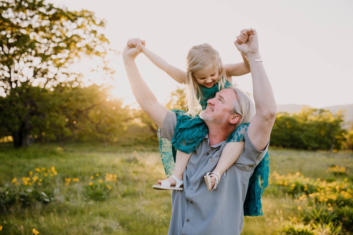 Dad and daughter laughing while she sits on his shoulders