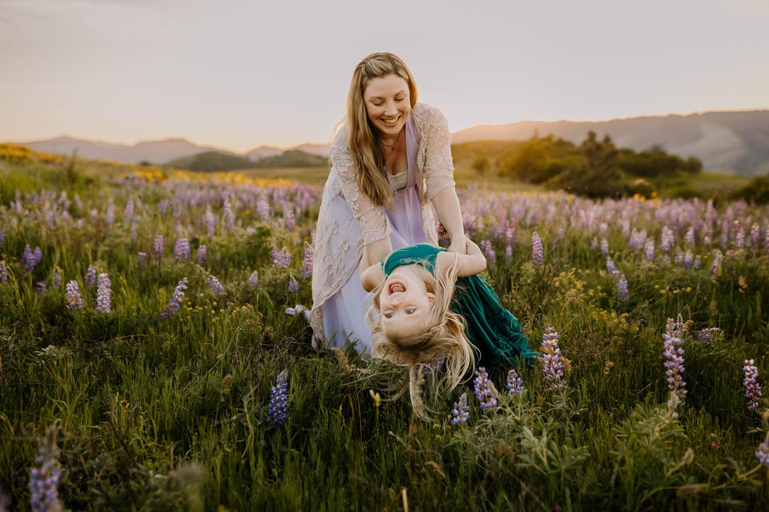 Mom dipping her laughing 5-year-old daughter in the lupine near hood river oregon