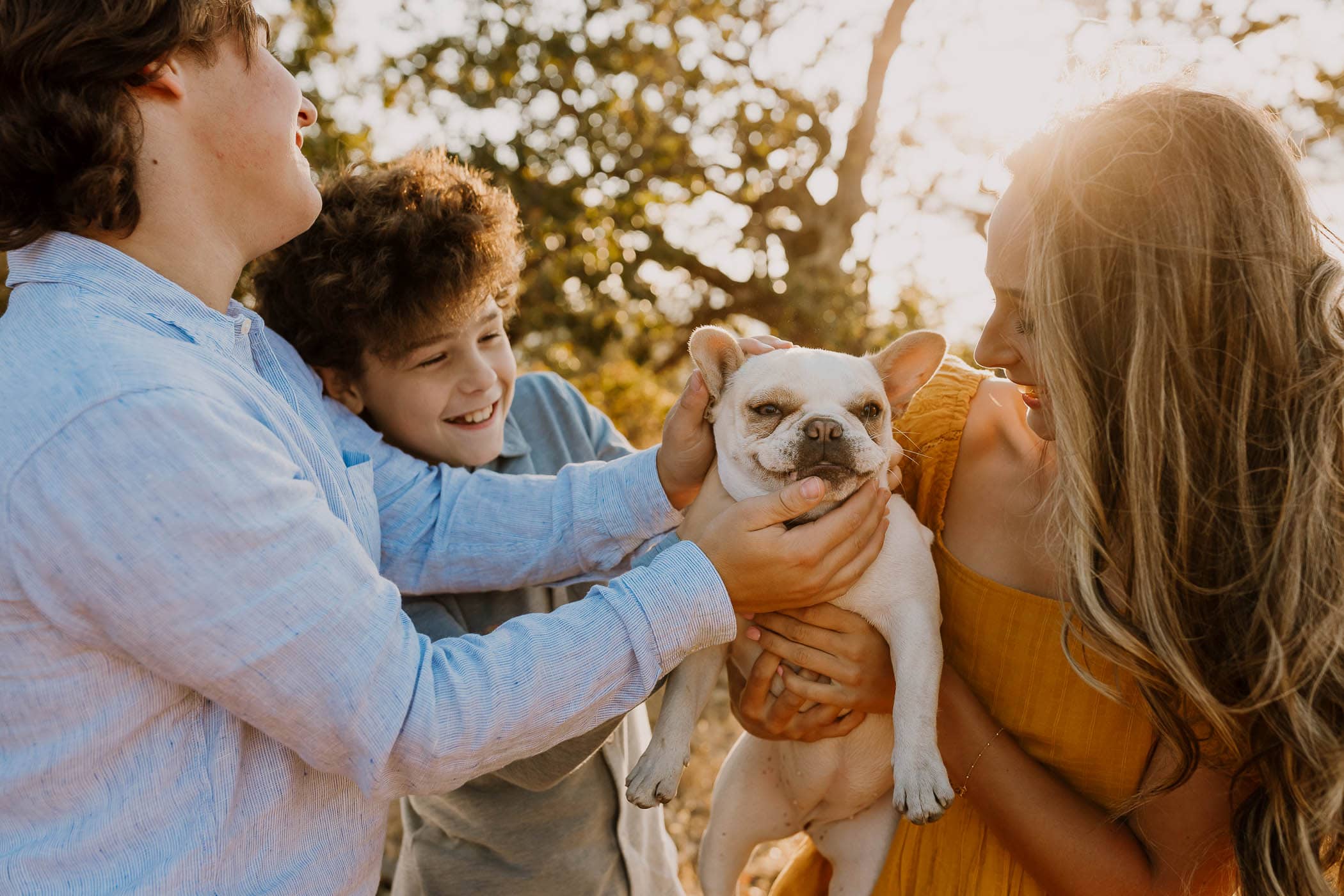 teenagers hugging their white dog during family photos