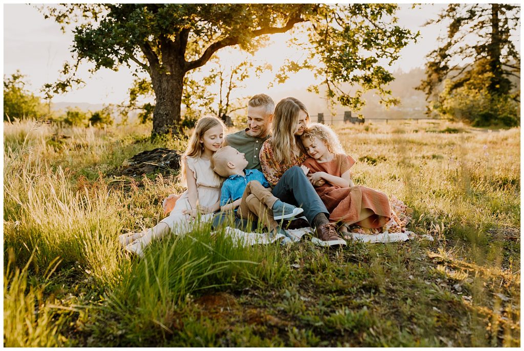 Adorable family cuddling on a blanket sitting during hour long family photos at golden hour
