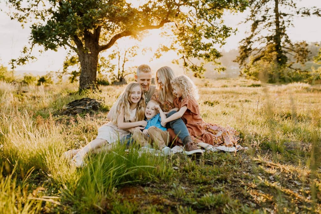 family cuddling while they tickle youngest child - why you shouldn't diy family photos