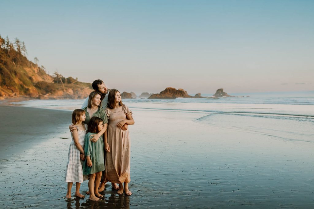 family cuddling close together on a beach - why you shouldn't try to take your own family photos