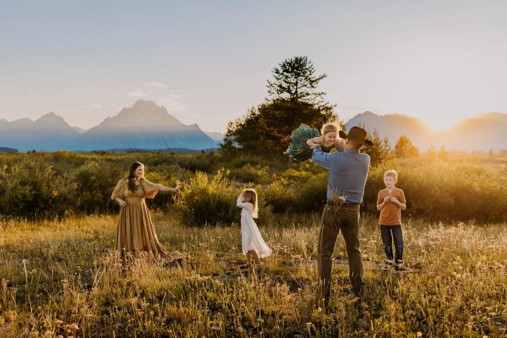 family playing and dancing with the grand tetons behind them during travel family photos