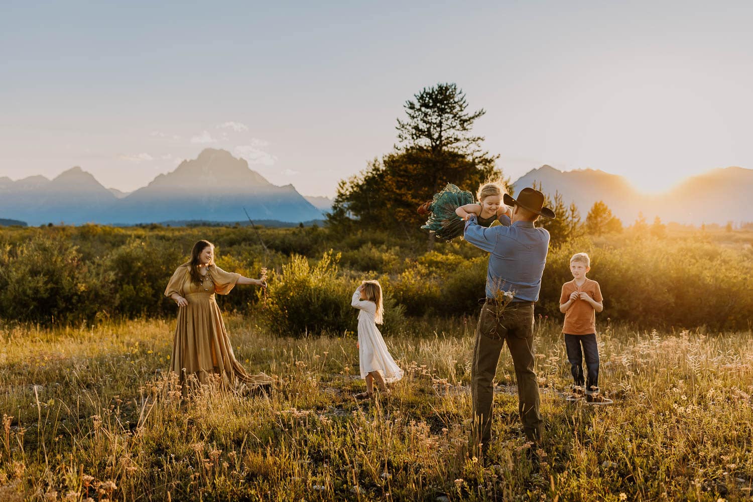 family playing and dancing with the grand tetons behind them during travel family photos