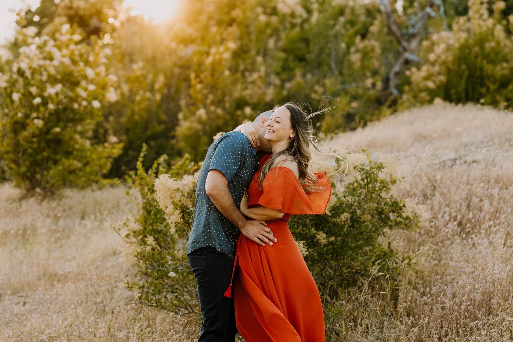 adorable couple hugging while the golden hour sun shines behind them during their photography session
