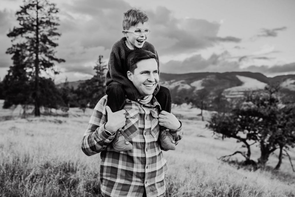 A dad with his son up on his shoulders during family photography session outside