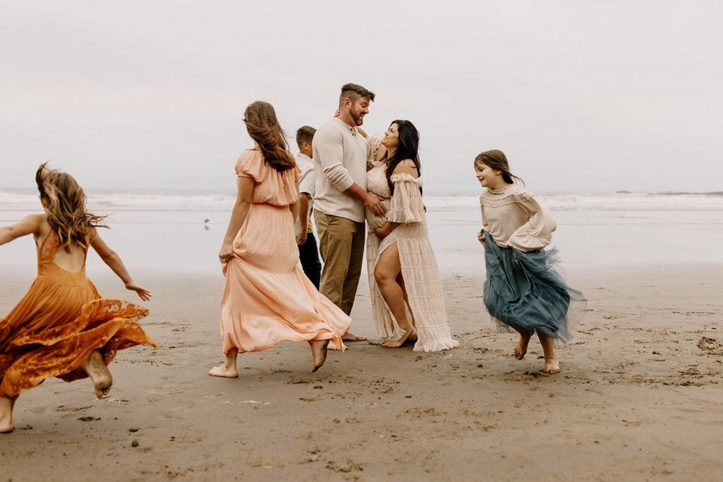 Large family dressed in neutral color scheme with a pop of color at the beach