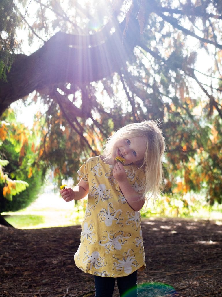 little girl standing under tree