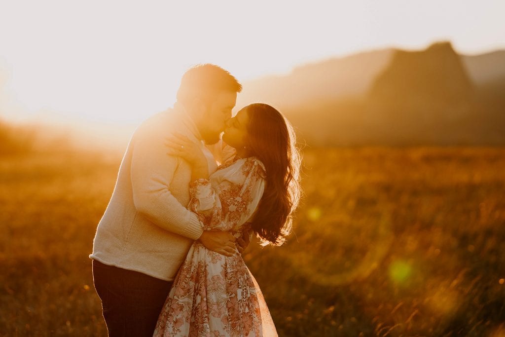 A couple embracing in a field with the sun shining through them