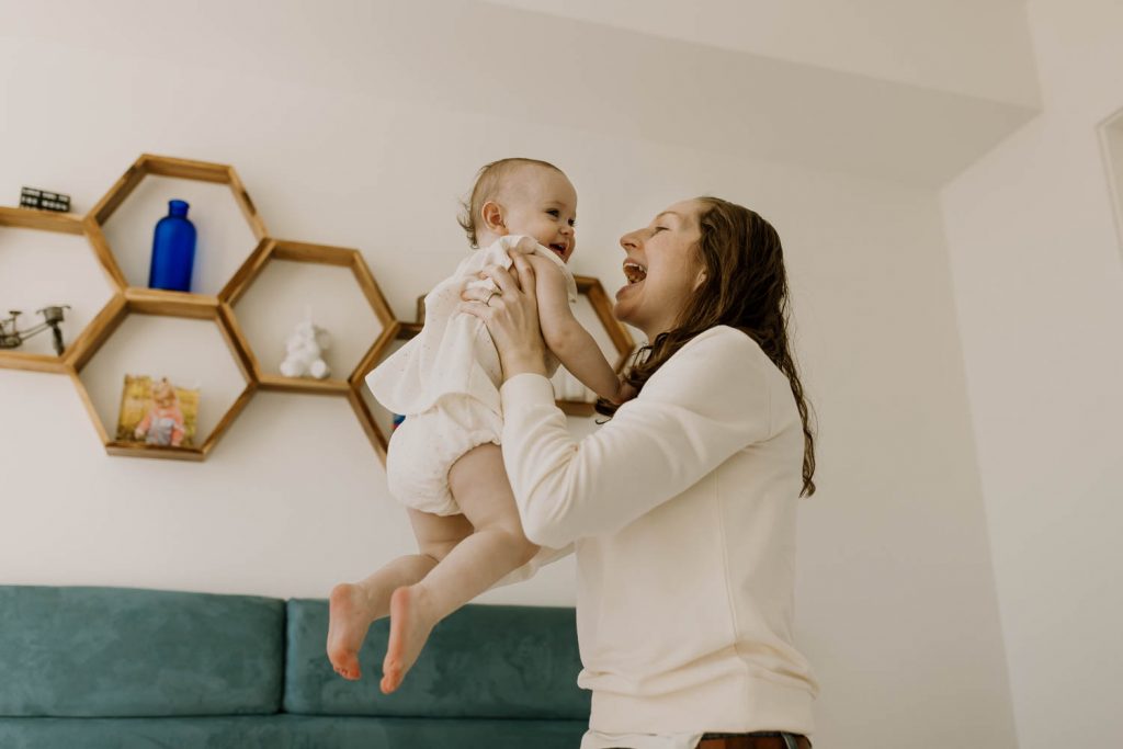 mom lifting baby girl up in the air during family photos
