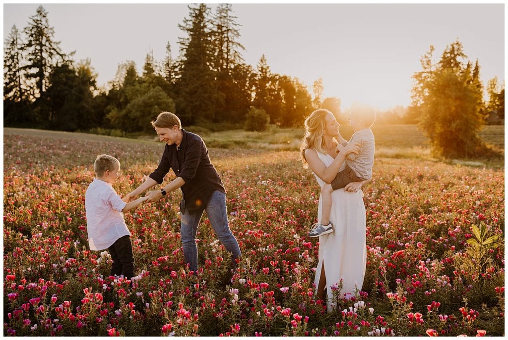 parents playing and dancing with their kids in a filed of pink flowers during family photos