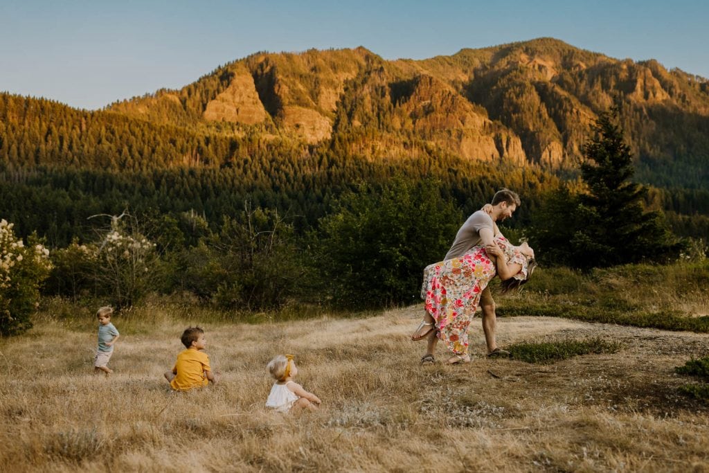 Dad dancing with mom while kids run around in the mountains