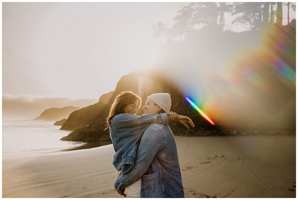 Man picking up his fiancee with a rainbow lens flare created with the lensbaby omni filter