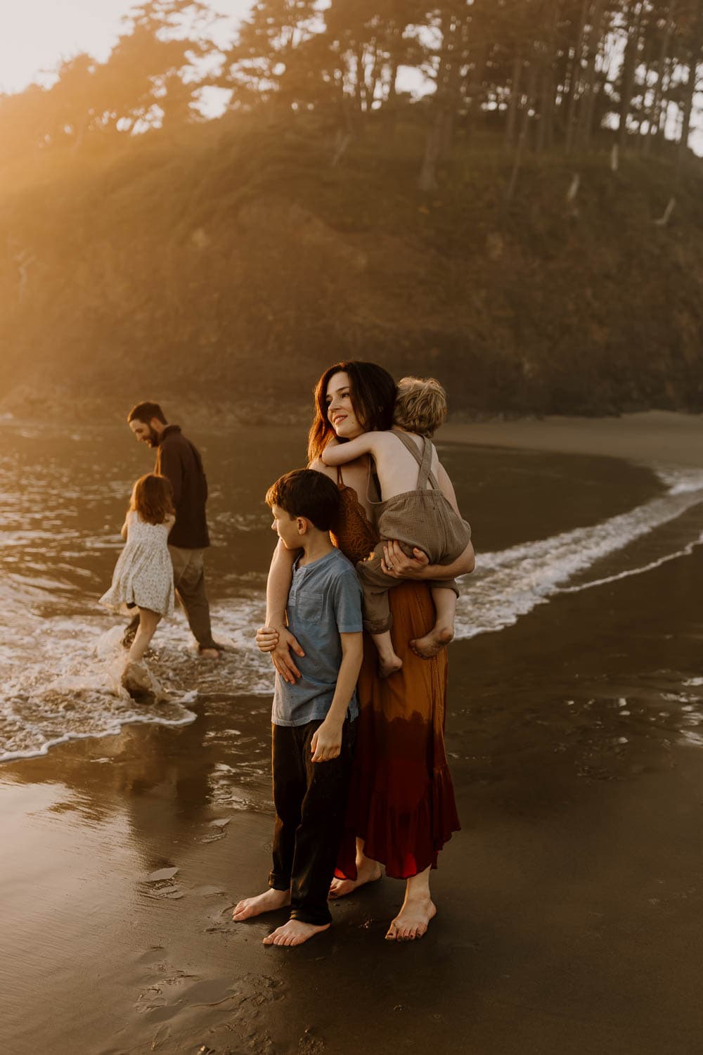 family of five relaxing at the beach together at sunset