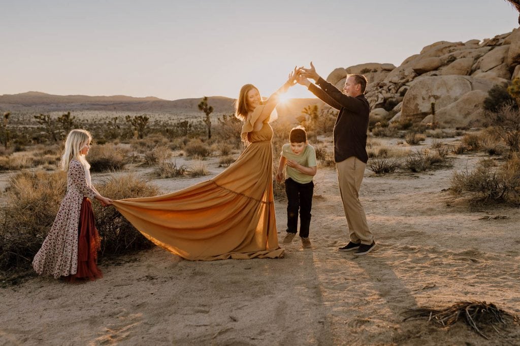 Son runs under parents arms while daughter holds up moms dress during family photoshoot