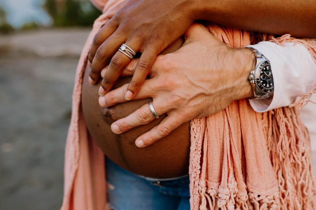 closeup of mom and dads hands on pregnant belly