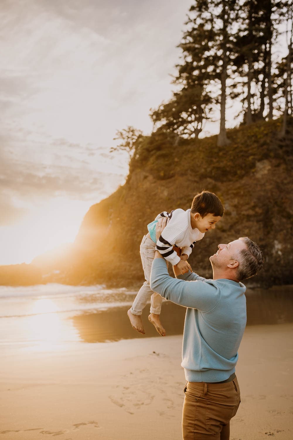 Dad lifting son in the air at the beach