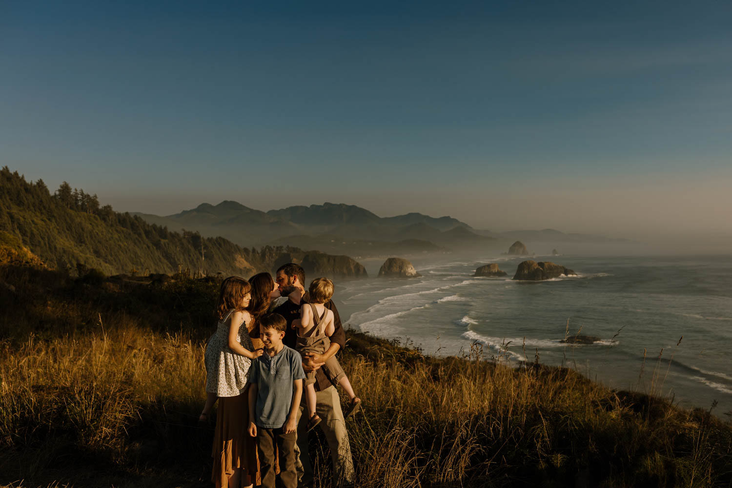 Family cuddling at the Ecola State Park with cannon beach behind them