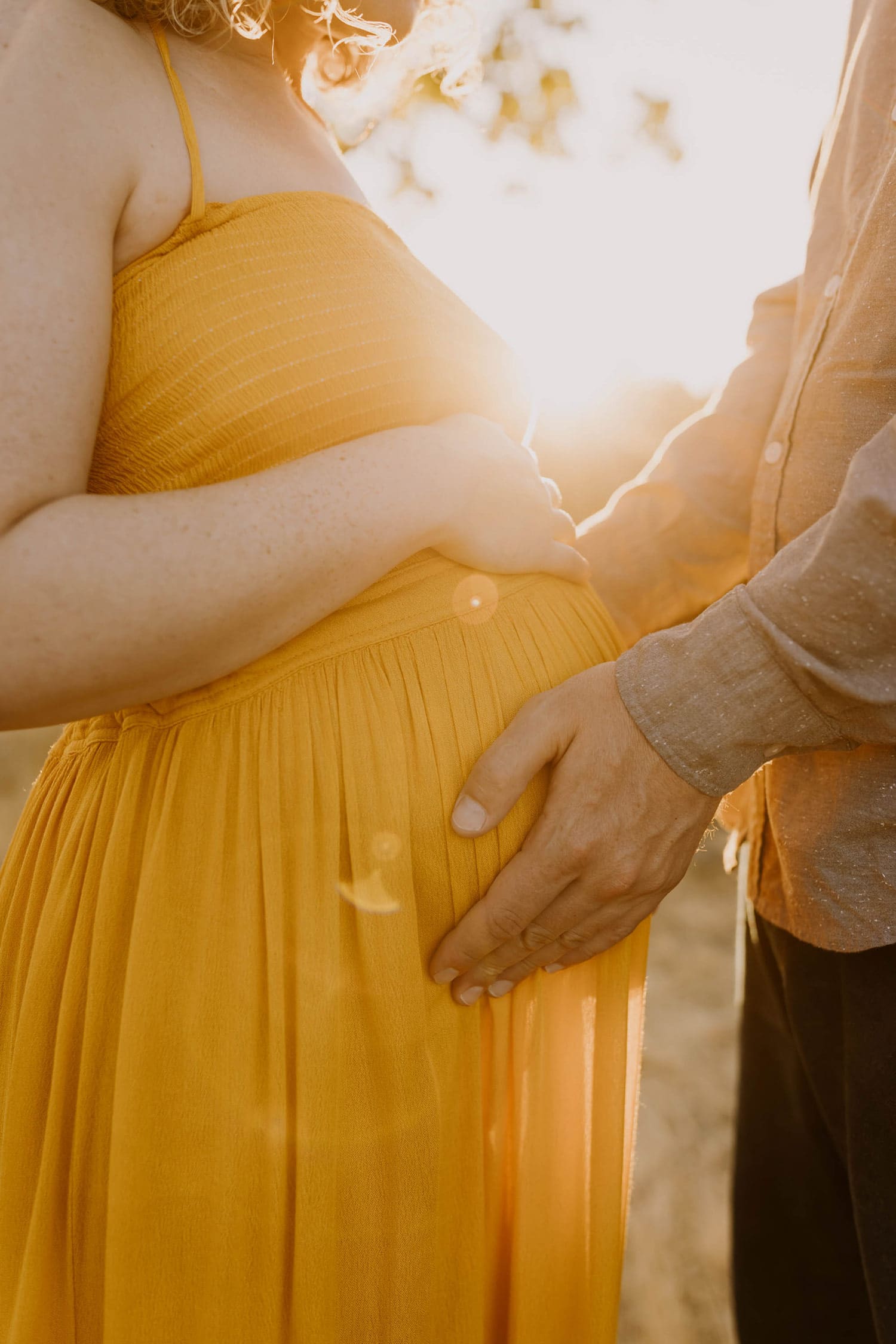 pregnant woman in mustard yellow dress with husband