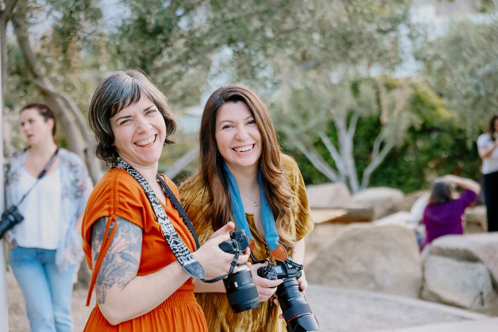 Two family photographers smiling while holding Canon cameras and lenses